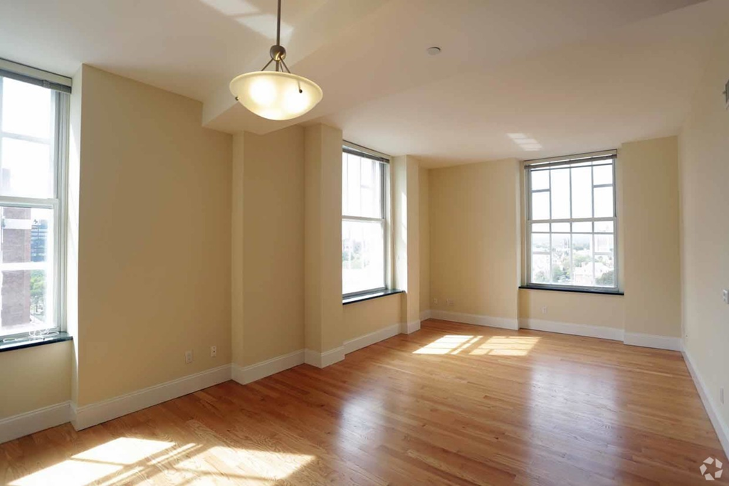 an empty living room with wood floors and two windows