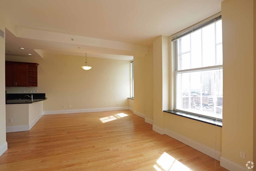 an empty living room with a large window and wooden floors
