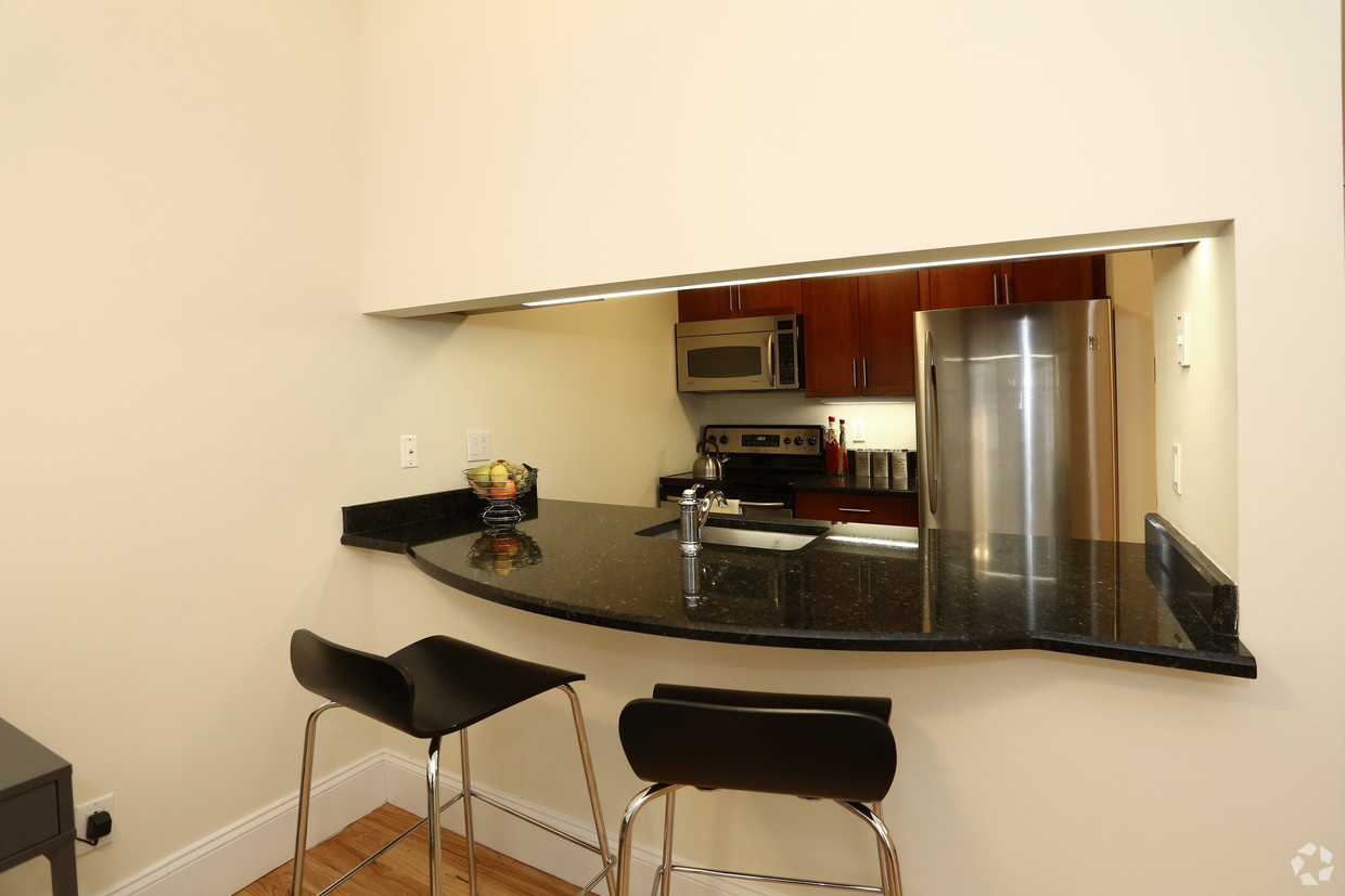 a kitchen with a black counter top and a stainless steel refrigerator