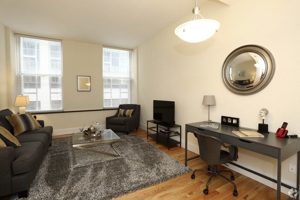 a living room with a couch and a desk and a mirror