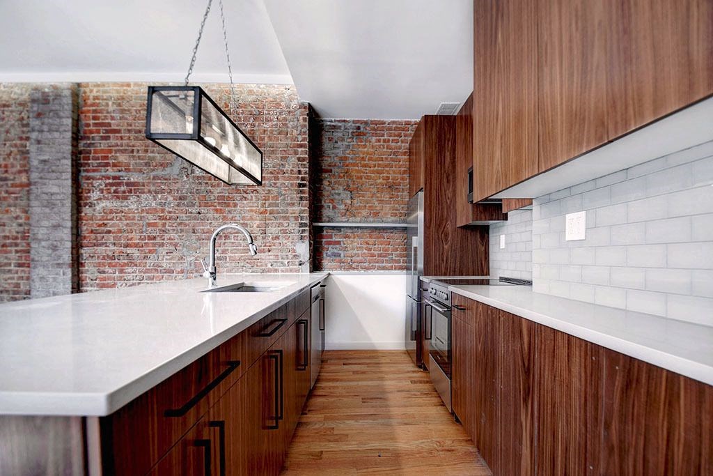 a kitchen with wooden cabinets and a brick wall
