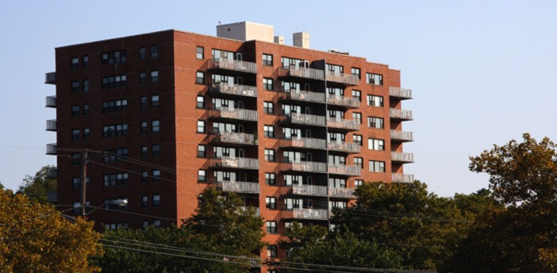 a tall red brick apartment building against a blue sky