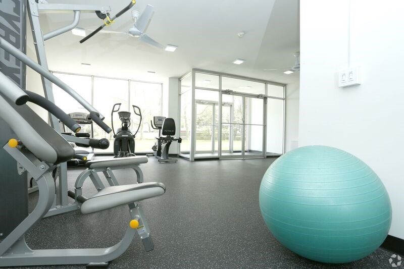 a gym with cardio equipment and an exercise ball