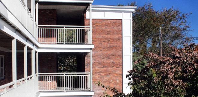 a red brick building with a balcony and a tree