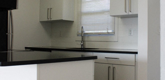 a kitchen with white cabinets and a sink and a window