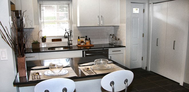 a small kitchen with white cabinets and a table and chairs
