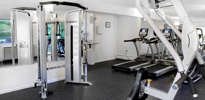 a gym with cardio equipment and weights on the floor
