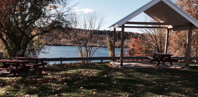 a picnic pavilion with a river in the background