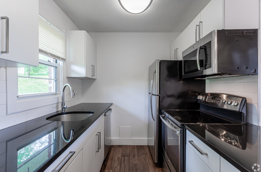 A modern kitchen with black countertops and stainless steel appliances.