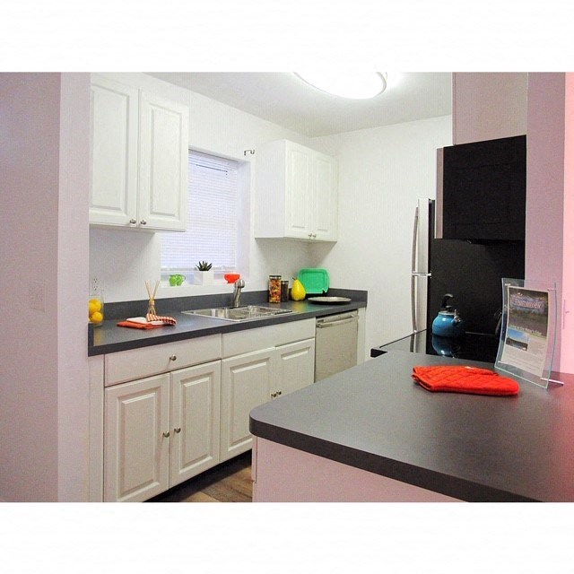 a kitchen with white cabinets and a black refrigerator