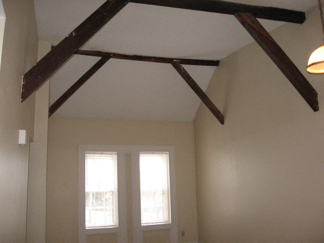 exposed rafters in a living room with windows