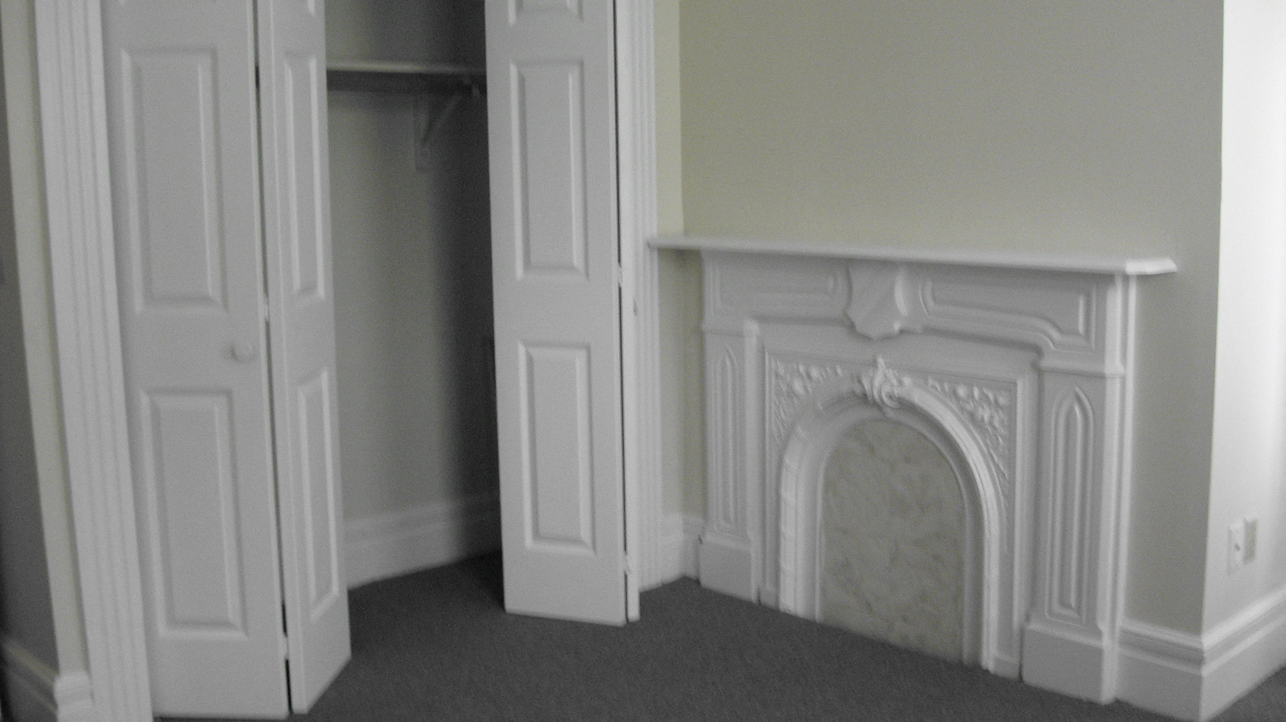 an empty room with a fireplace and a closet