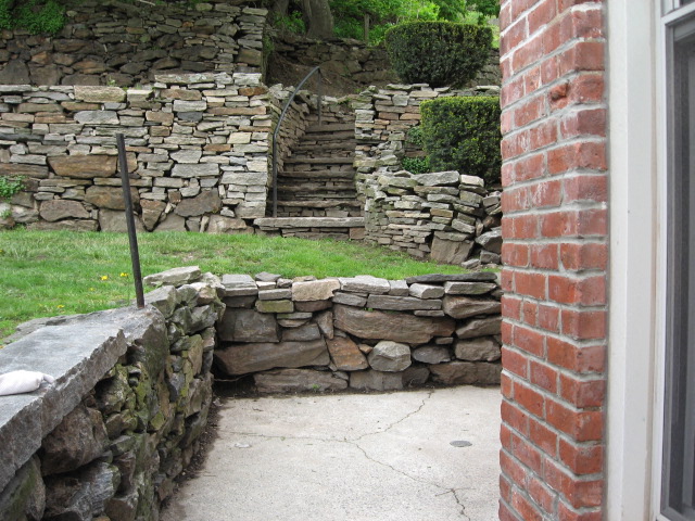 a stone retaining wall with steps in a garden