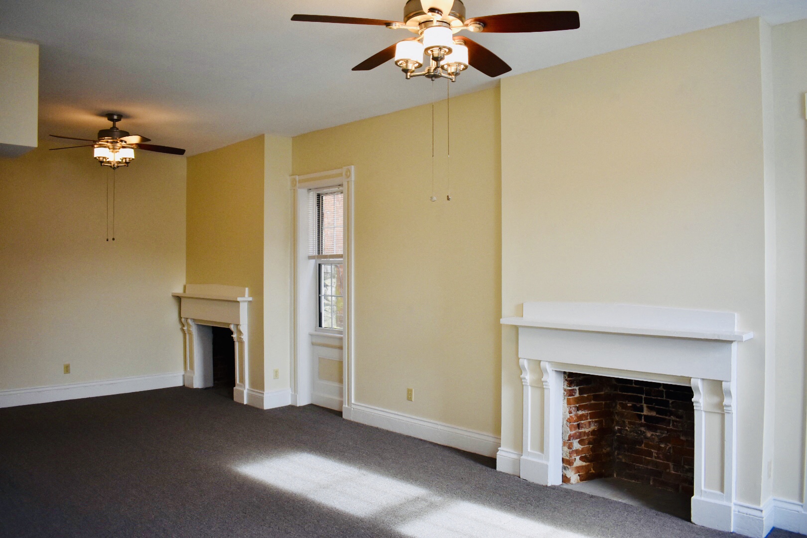 an empty living room with a fireplace and a ceiling fan