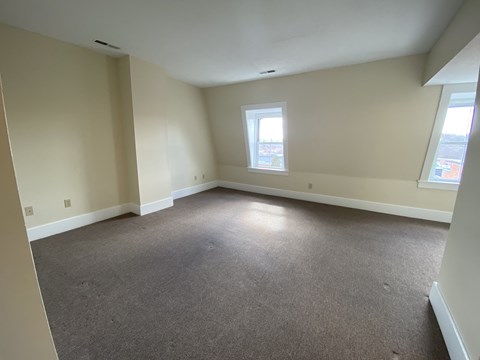 a living room with carpet and two windows