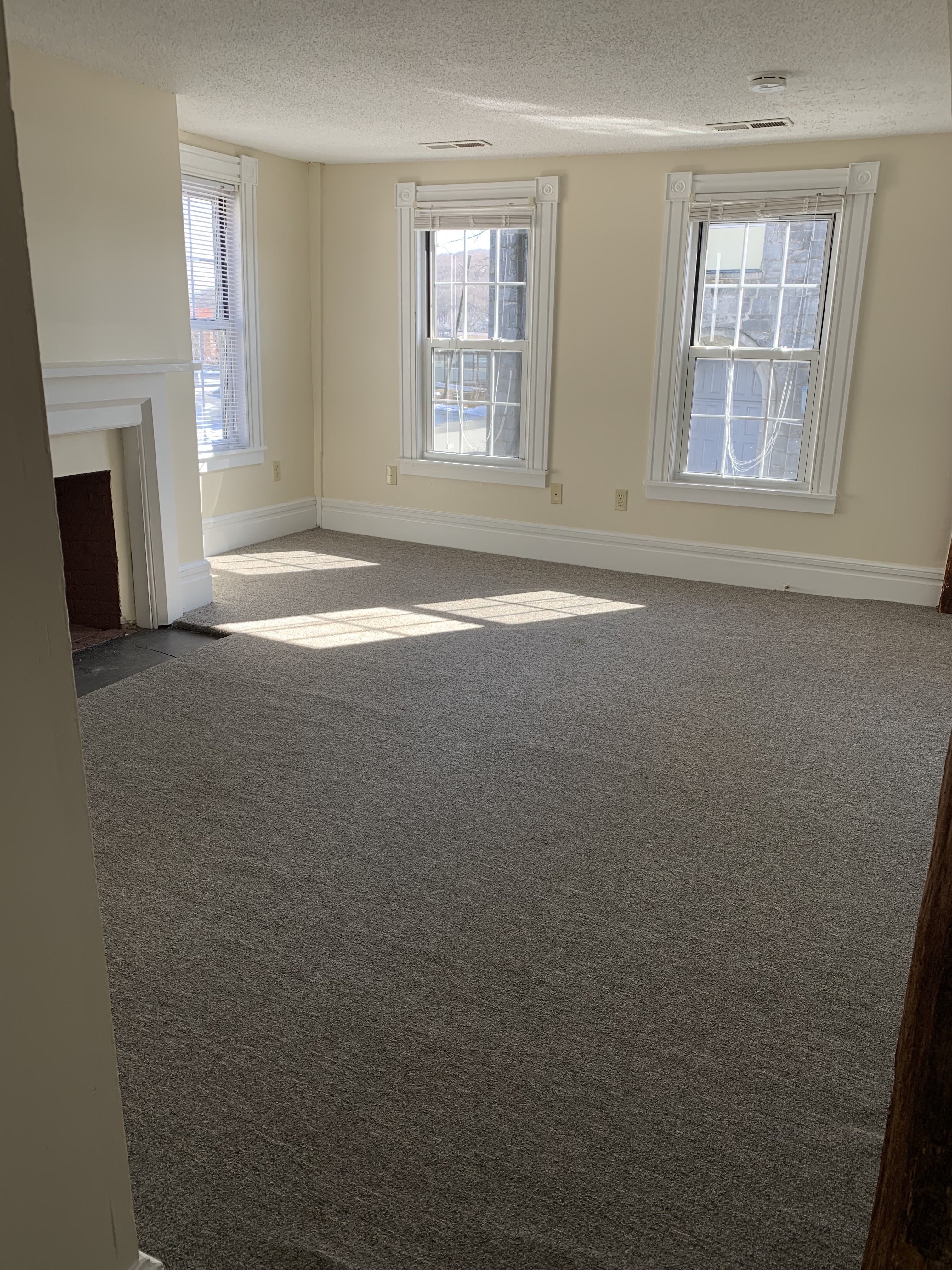 the living room of an empty house with three windows