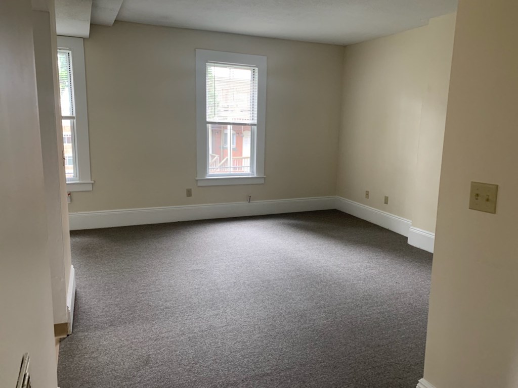 a room with a carpeted floor and two windows