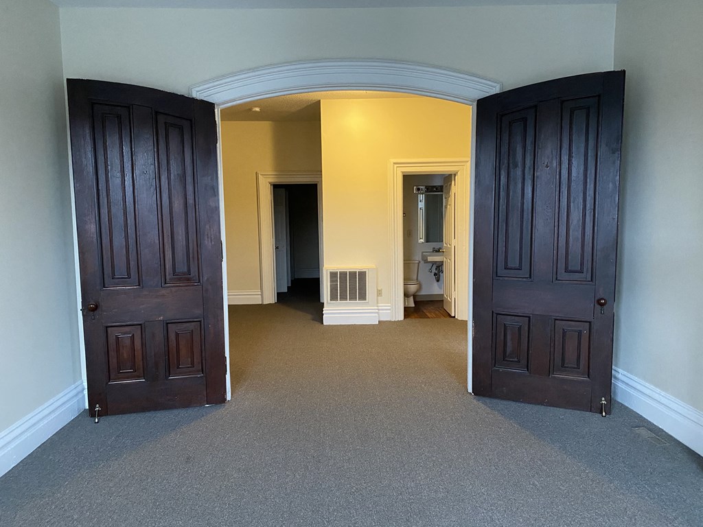 a room with two doors and a bathroom in the background