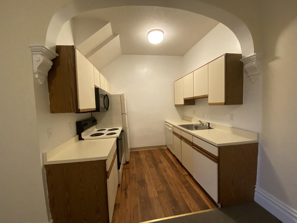 an empty kitchen with wooden cabinets and a stove and a sink