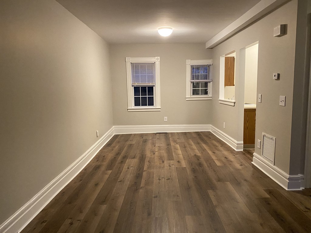 an empty living room with hardwood floors and a window