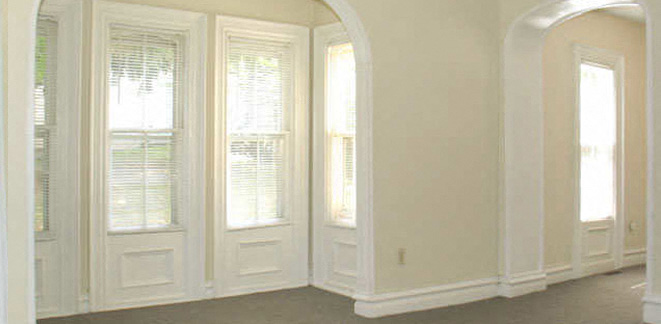 an arched doorway and three windows in a white room