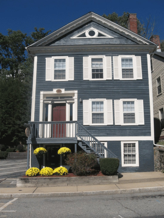 a blue house with white shutters and a porch with yellow flowers