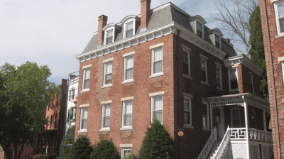 a red brick house with white windows on a street