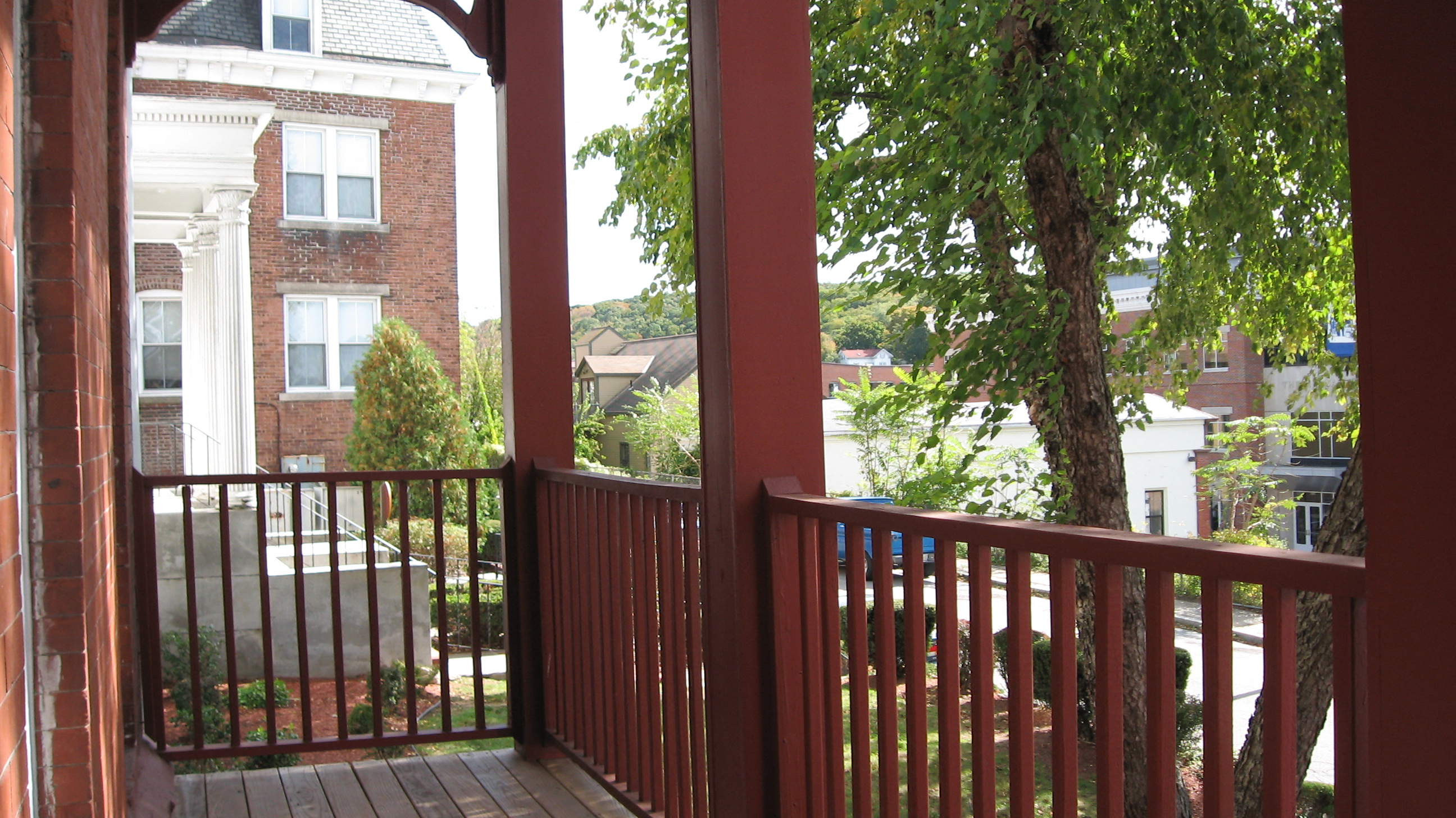 a balcony with a tree and a house in the background