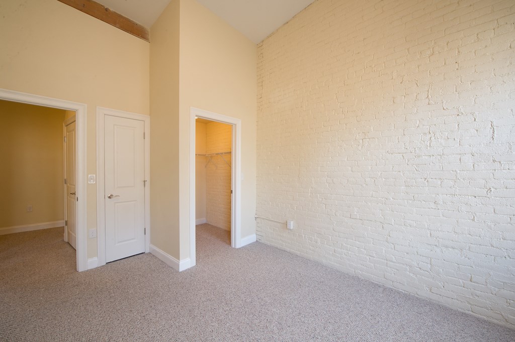 an empty room with a white brick wall and a door to a closet
