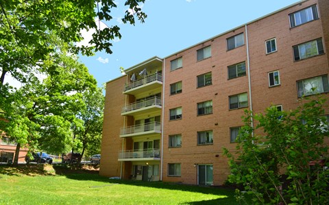 a large brick apartment building with a green lawn