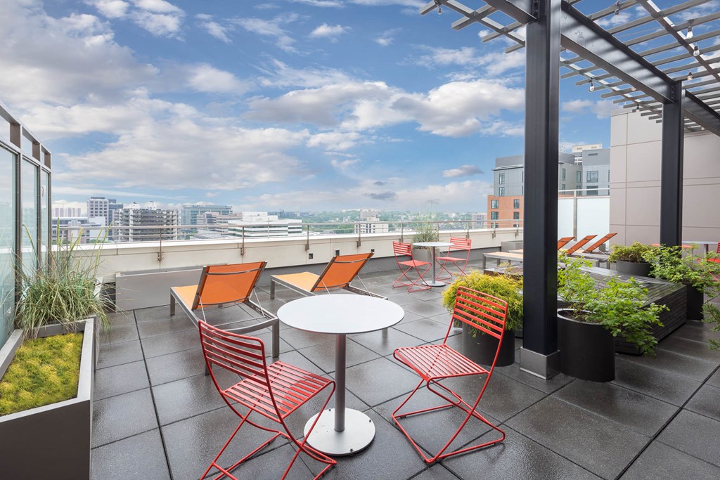 a patio with orange chairs and a table on a rooftop