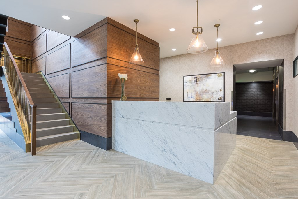 a marble reception desk in a lobby of a building with stairs