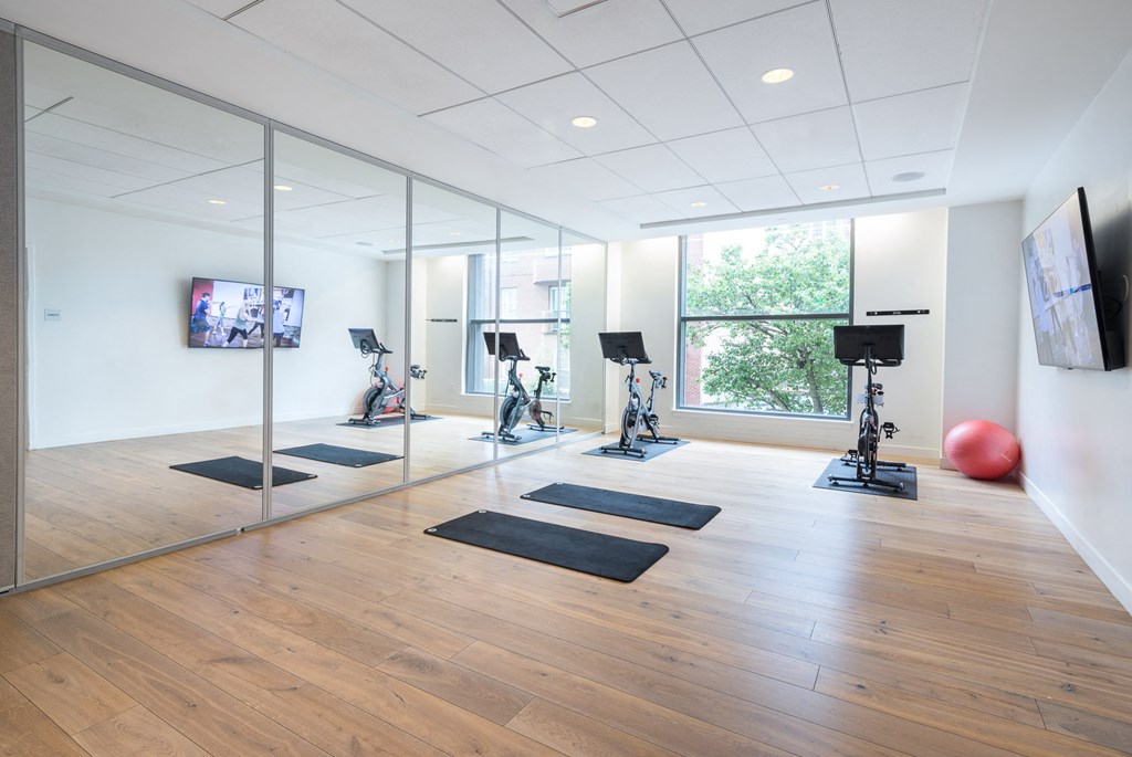 a yoga room with mirrors and yoga mats and a window