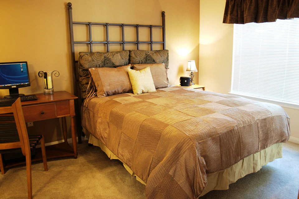 a bedroom with a bed and a desk with a computer