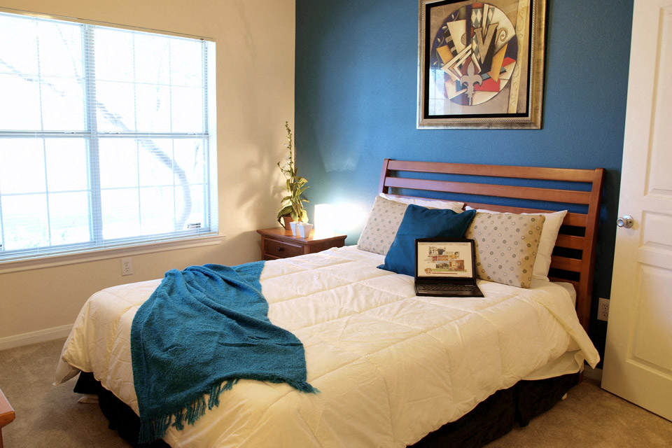 a bedroom with a bed and a laptop on top of it