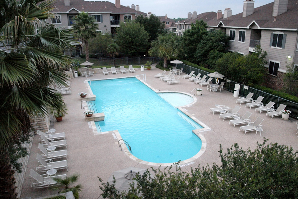 an aerial view of a swimming pool with chairs and umbrellas