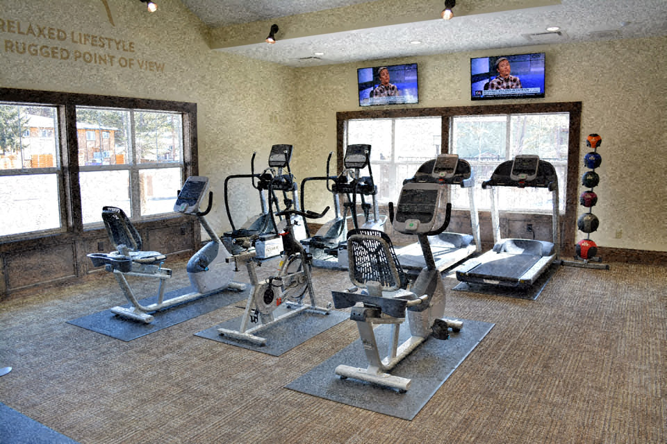 a gym with cardio equipment in a building with windows