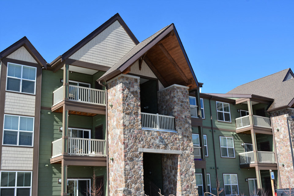 a green house with a stone facade and a wooden roof
