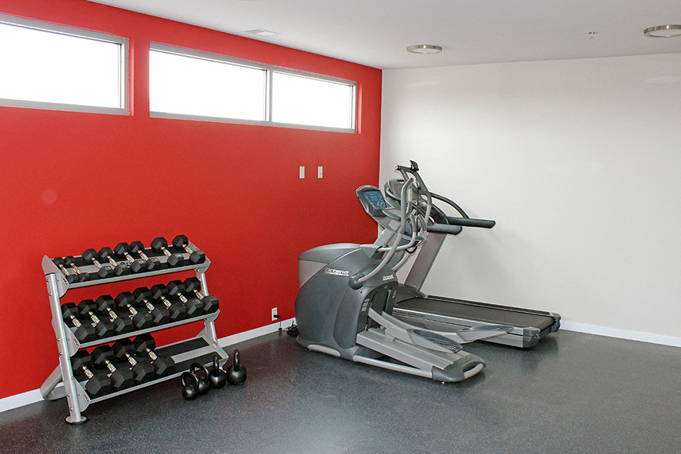 a home gym with a red wall and a workout machine