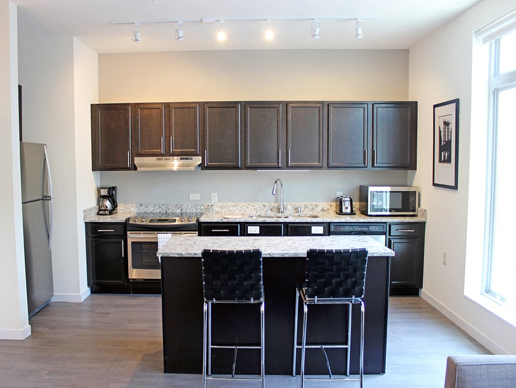 a kitchen with black cabinets and a bar with two stools