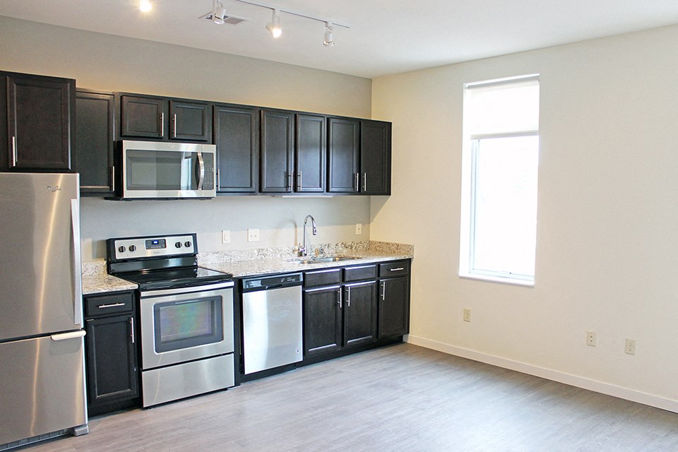 an empty kitchen with black cabinets and stainless steel appliances