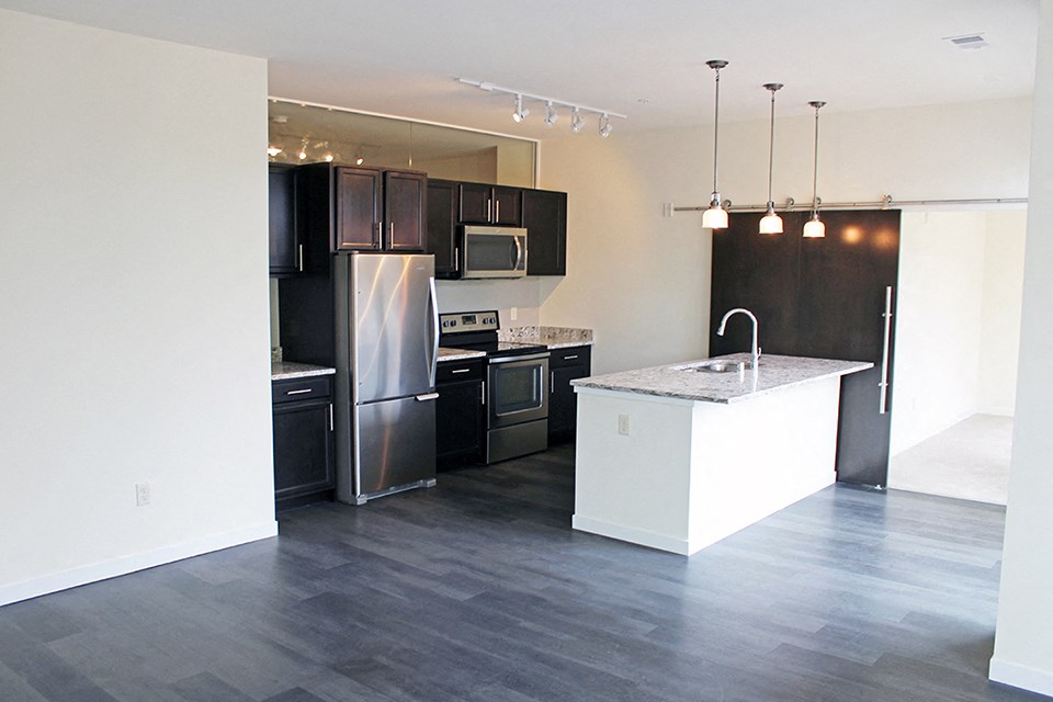 an empty kitchen with stainless steel appliances and black cabinets