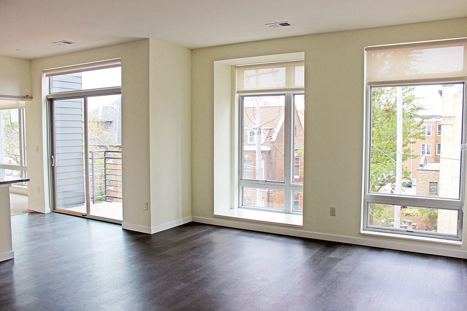 an empty living room with large windows and wood floors