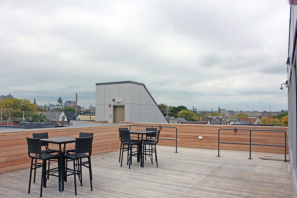 a roof deck with tables and chairs and a view of the city