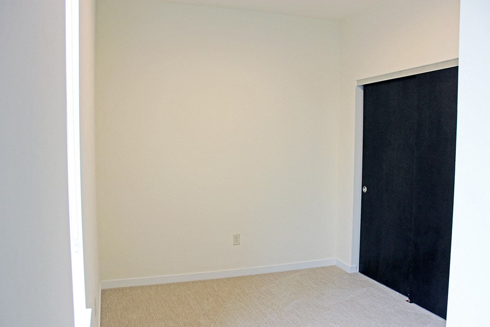 an empty room with a closet and a black door