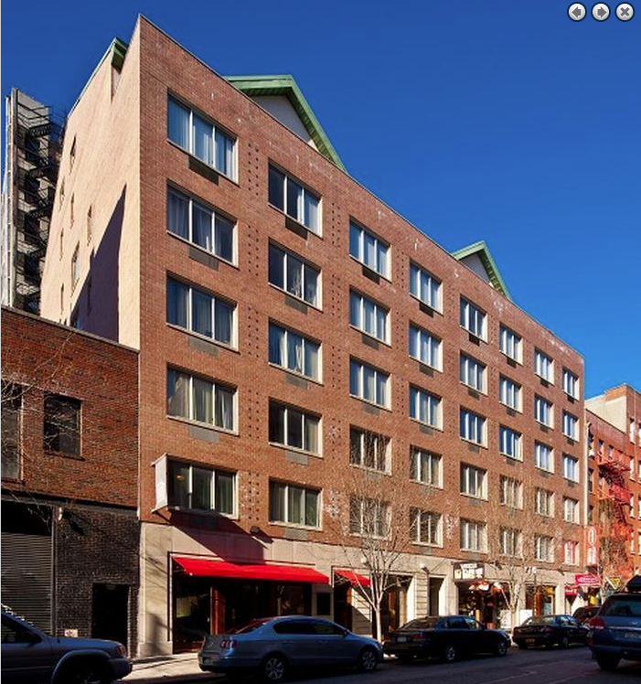 a tall brick building with cars parked in front of it