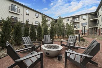 Adirondack chairs positioned around an outdoor firepit in courtyard at The Conrad