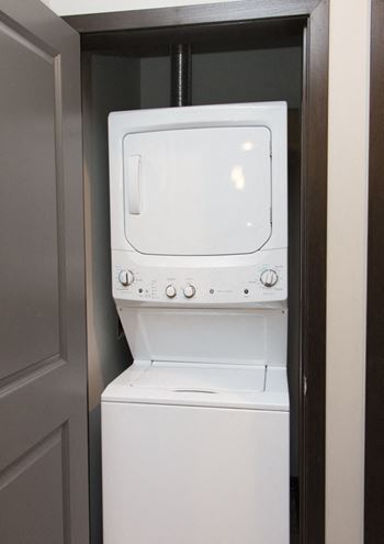 Stacked washer and dryer in a laundry closet at The Conrad