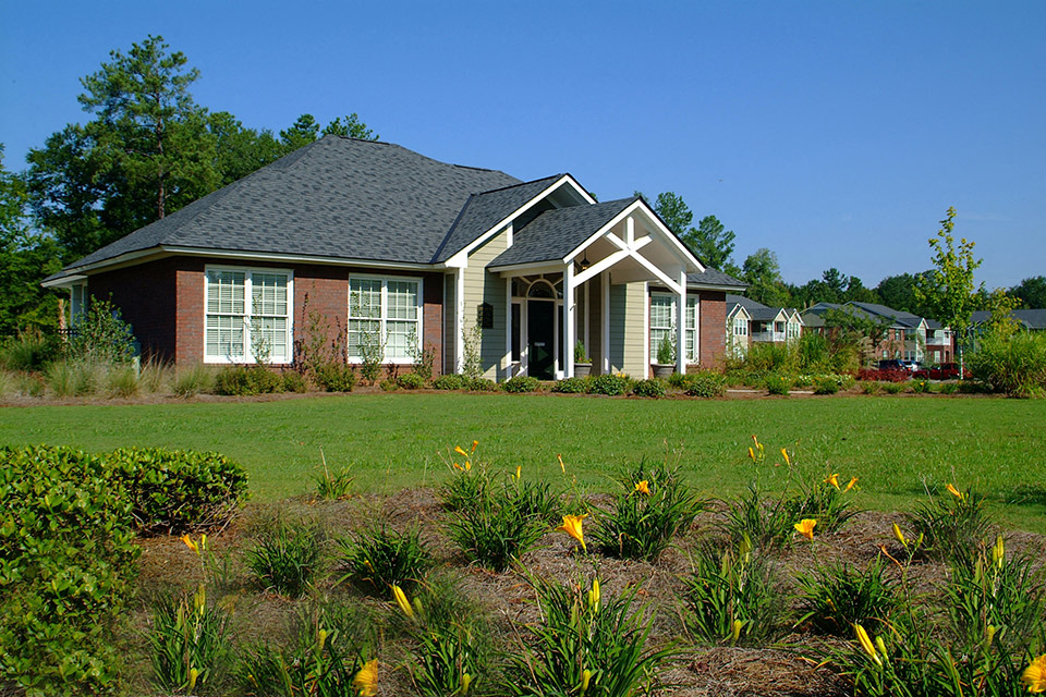 a house with a lawn and flowers in front of it