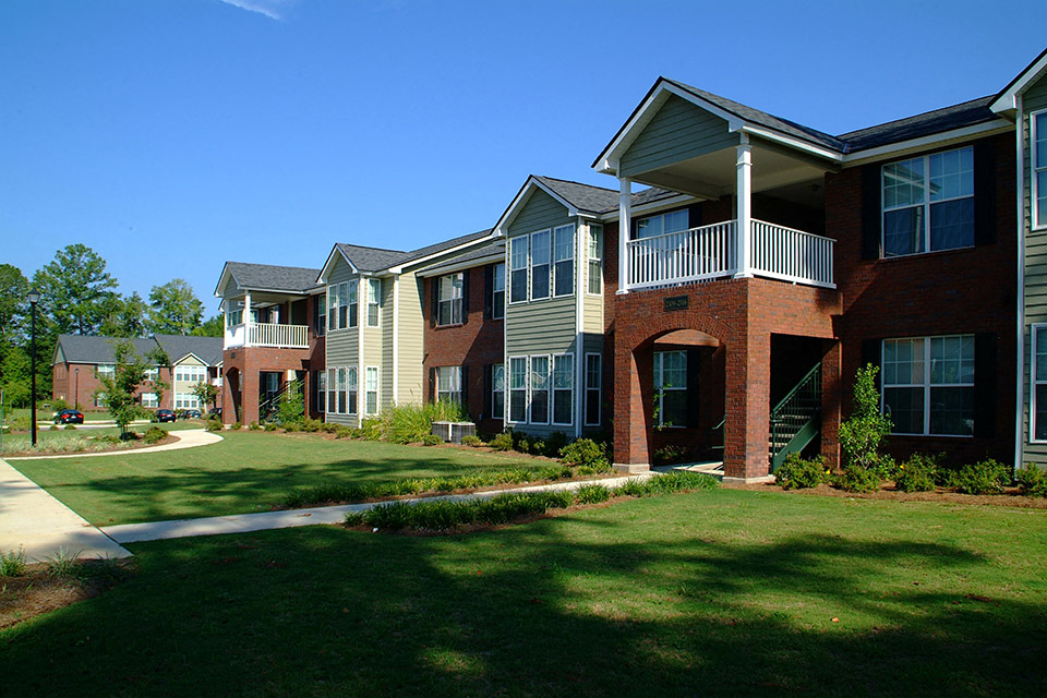 an apartment building with a lawn and a sidewalk